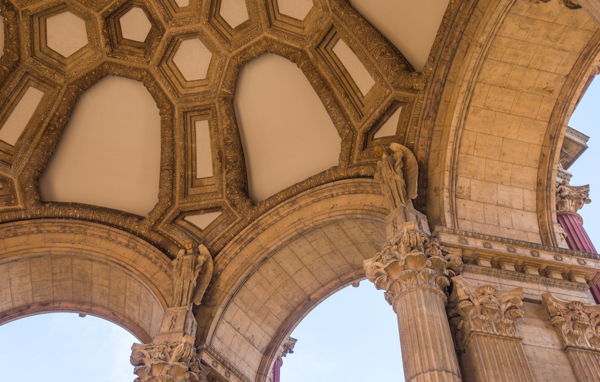Looking up at the ceiling of a building with arches and columns.