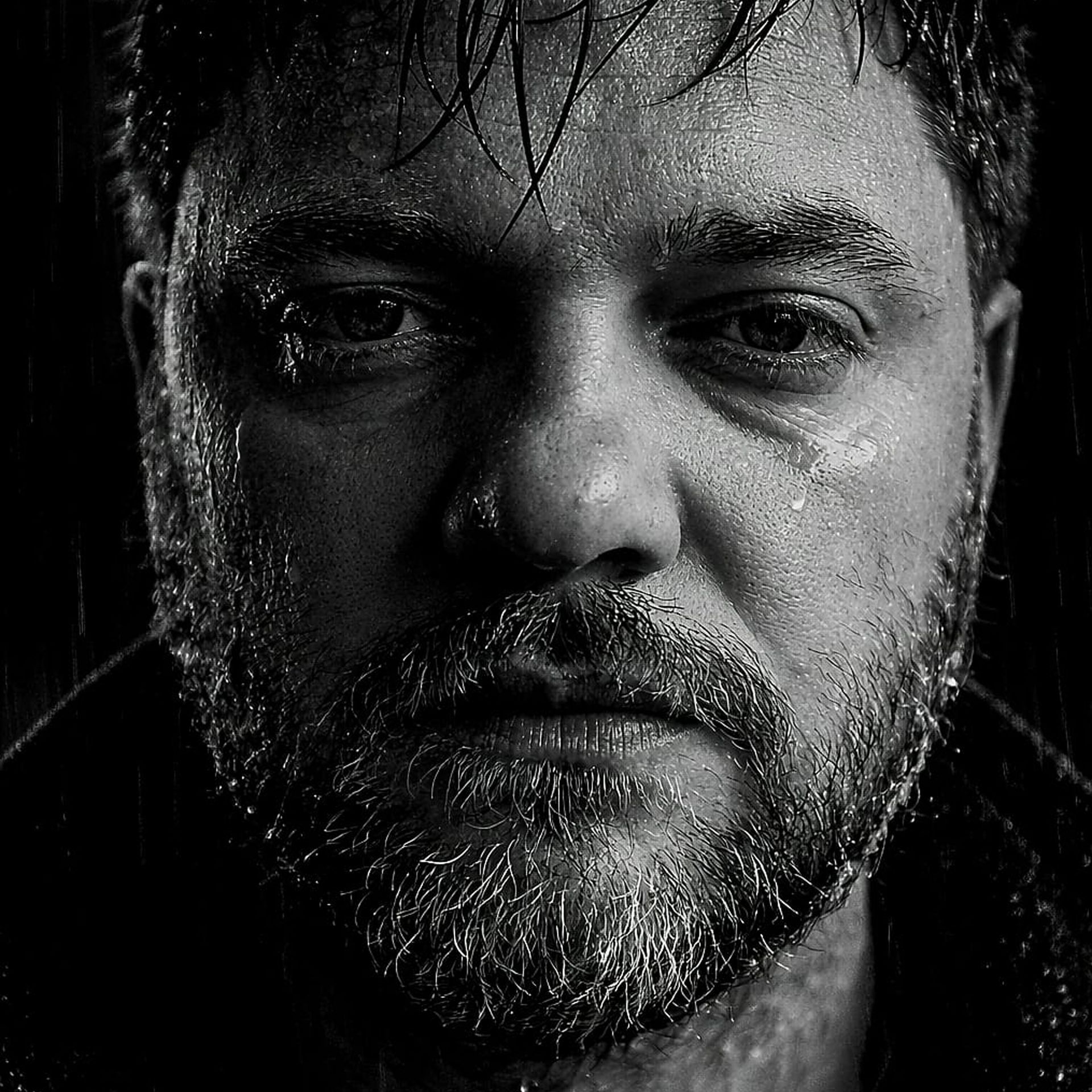 Close-up zwart-witfoto van LIWI GREY, nat van de regen, met een sombere uitdrukking.