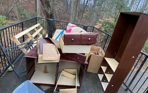 A pile of wooden furniture is sitting on top of each other on a balcony.
