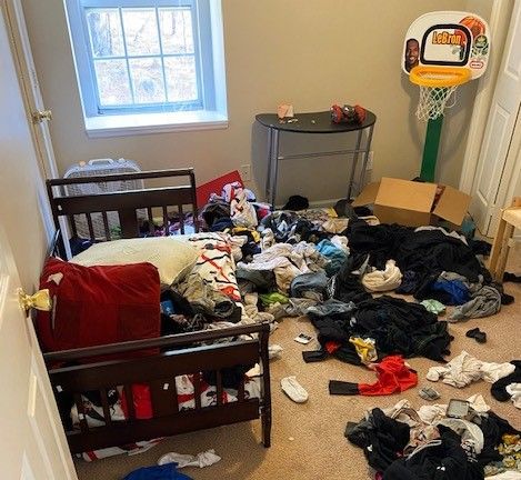 A messy bedroom with a basketball hoop and a bed.