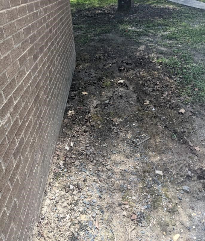 A brick wall with a lot of dirt next to it.
