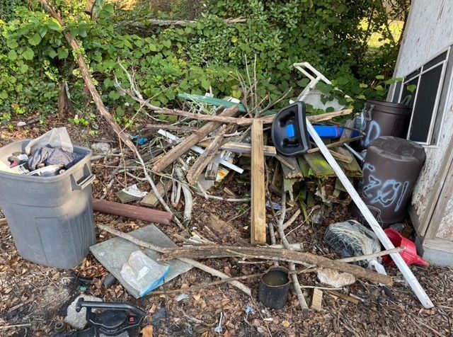 A pile of trash is sitting on the ground next to a shed.