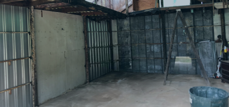 An empty room with a ladder and a trash can in it.
