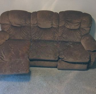 A brown couch is sitting on a carpeted floor in a living room.