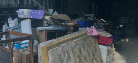A pile of mattresses , chairs , and other furniture is sitting on the ground.
