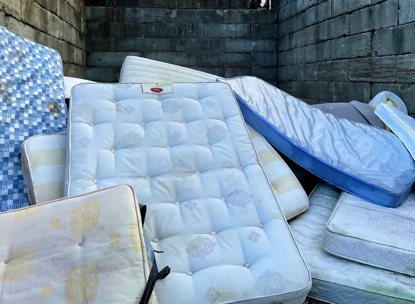A pile of mattresses are stacked on top of each other in a room.