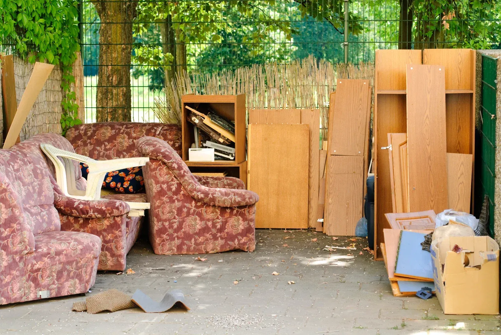 A bunch of furniture is sitting on the ground in a yard.