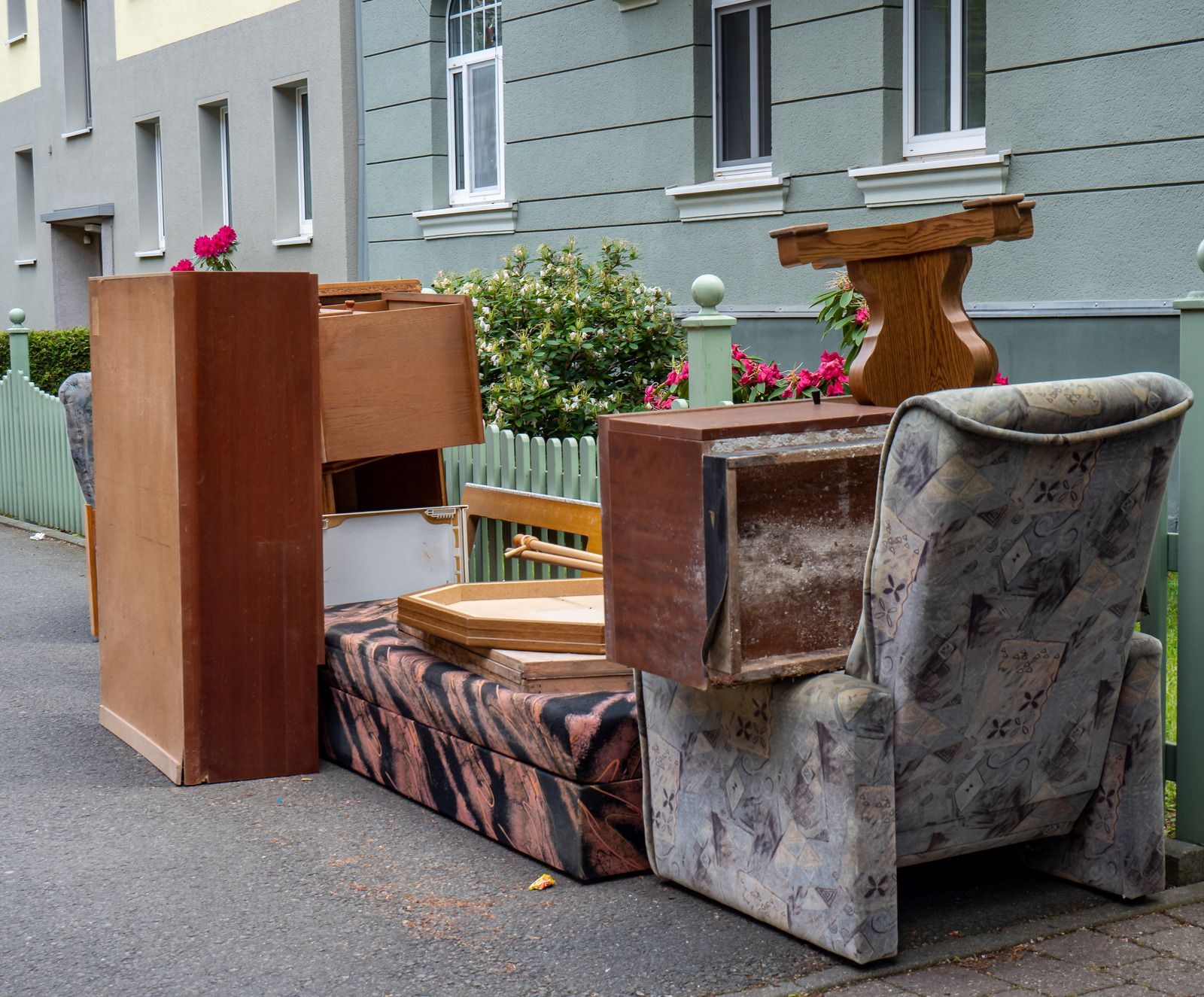 A pile of furniture is sitting on the side of the road in front of a building.