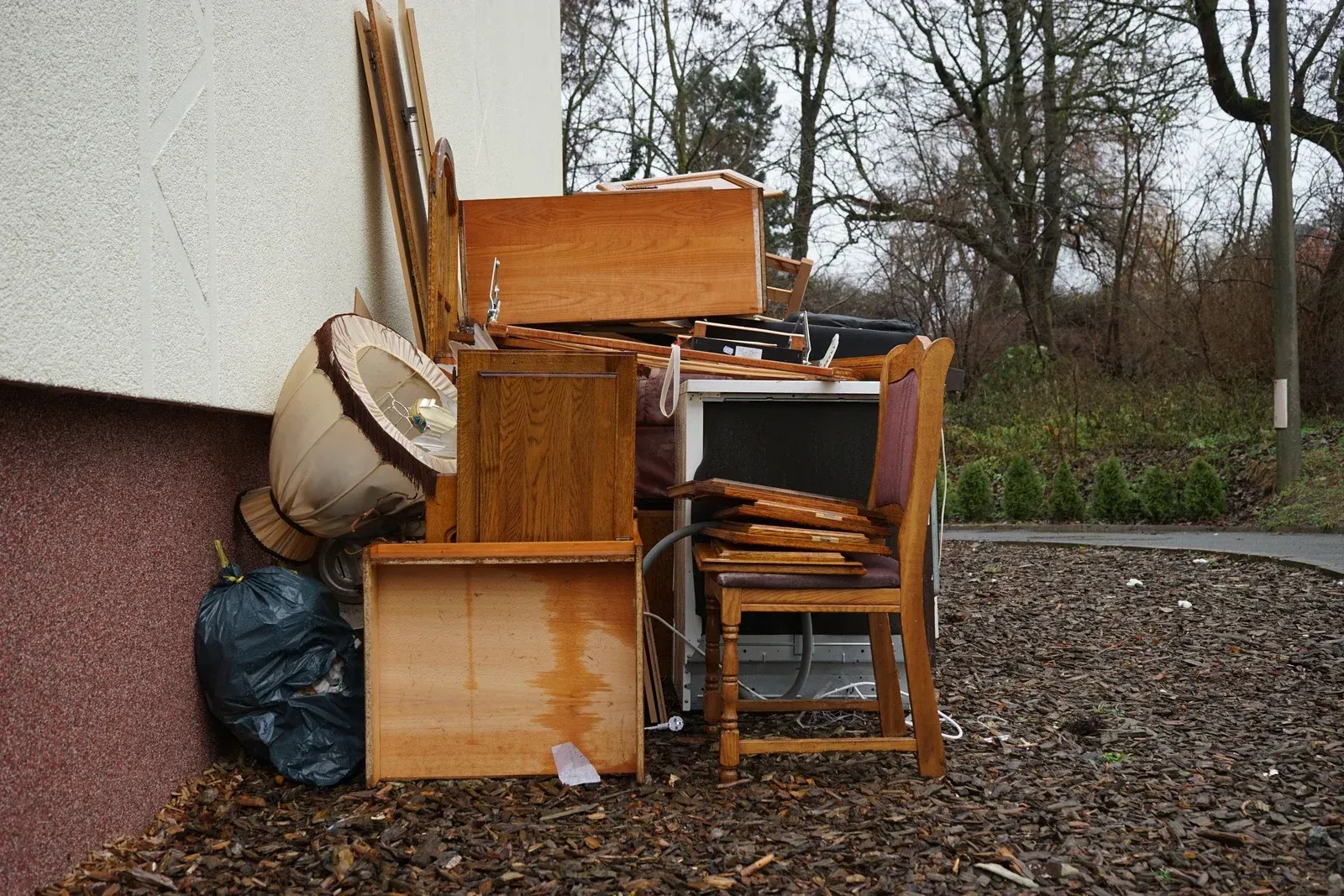 A pile of wooden furniture sits outside of a building