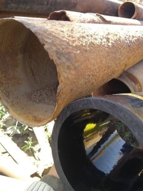 Una comparación entre una tubería de metal desgastada y oxidada y una tubería lisa, oscura y sin corrosión.