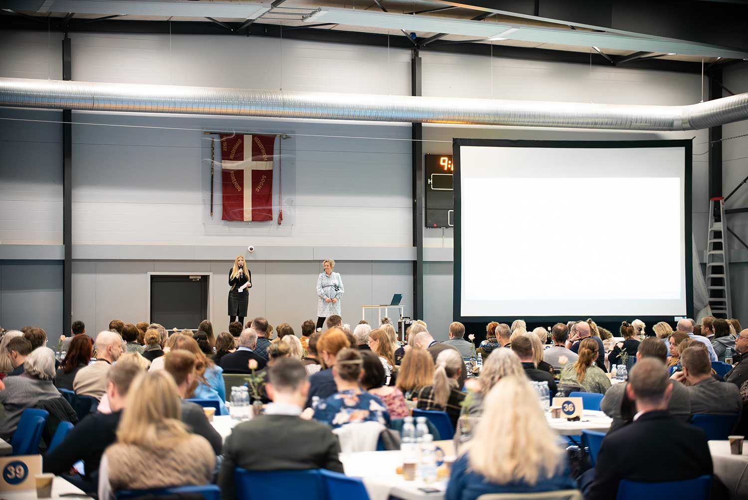 En kvinde spiller badminton på en rød bane.
