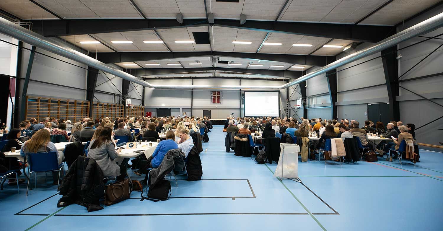 En kvinde spiller badminton på en rød bane.