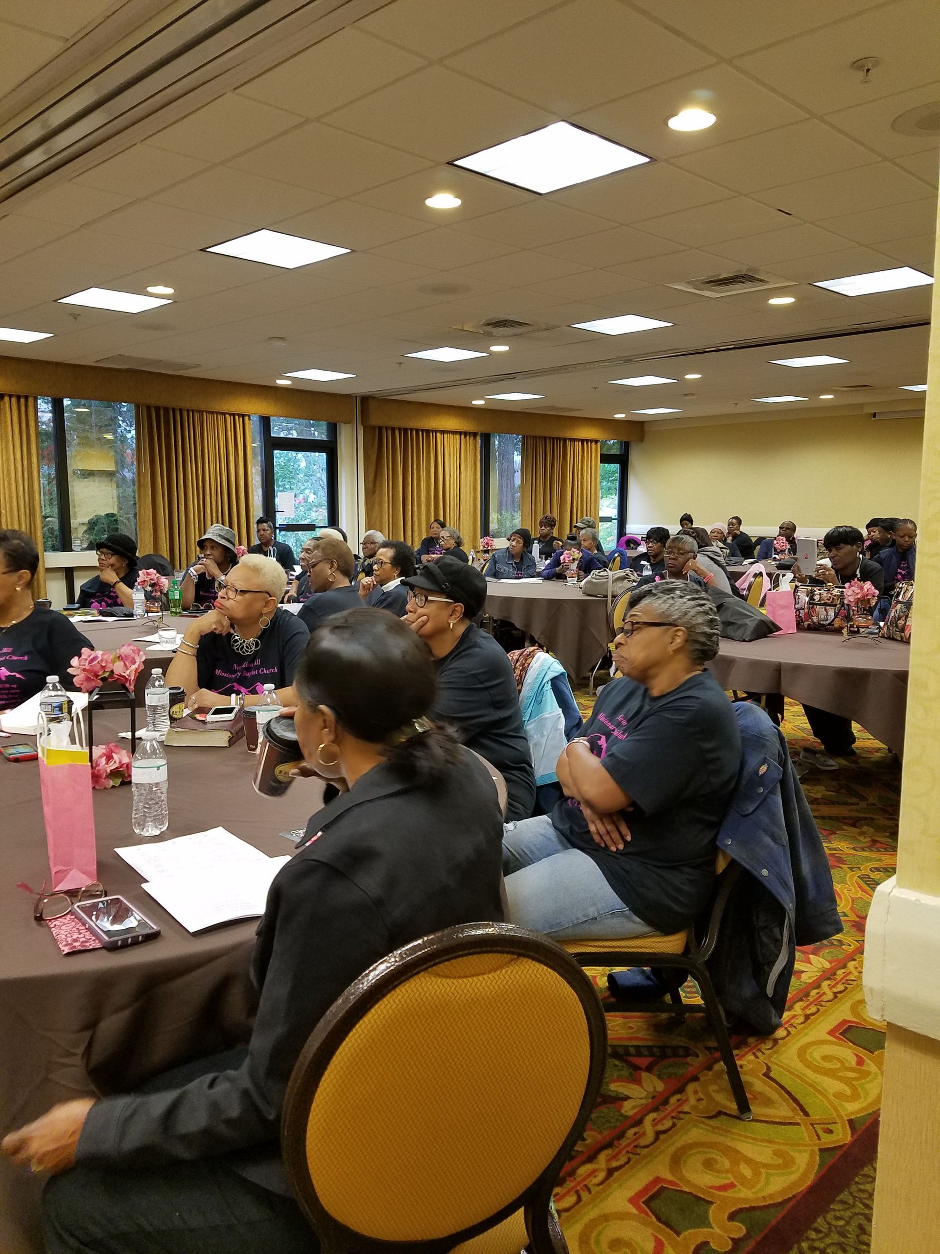 A group of people are sitting in a church reading books.