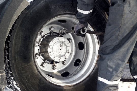 A man is changing a tire on a truck with a wrench.