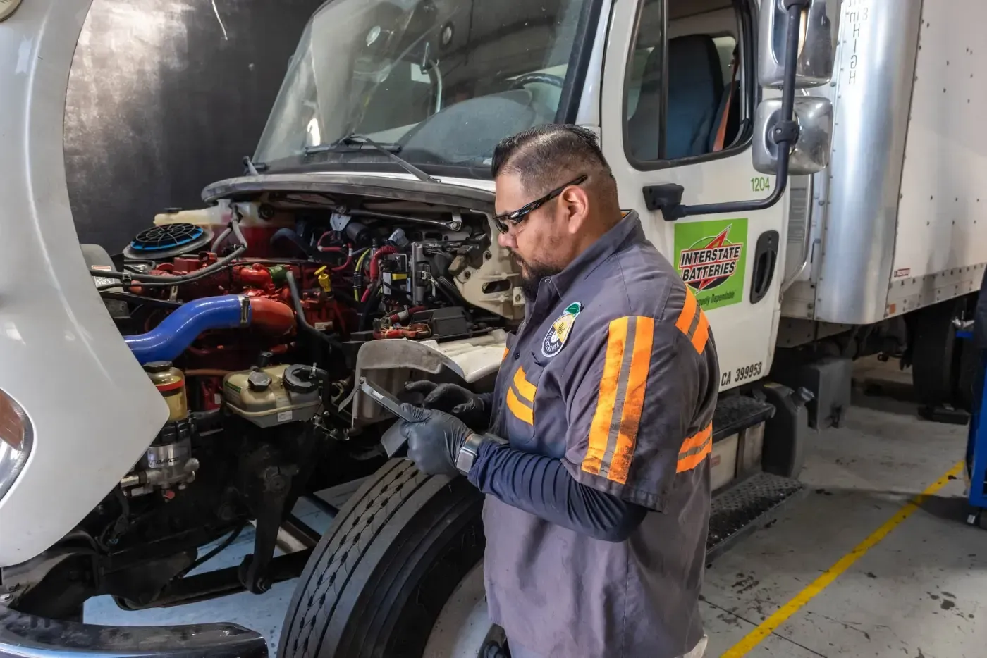 A man is working on the engine of a truck in a garage.