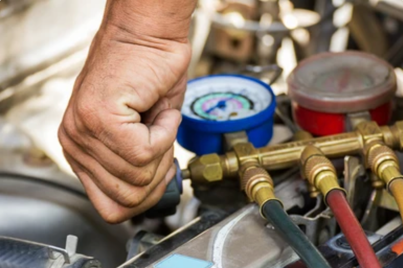 A man is working on a car with a gauge in his hand.