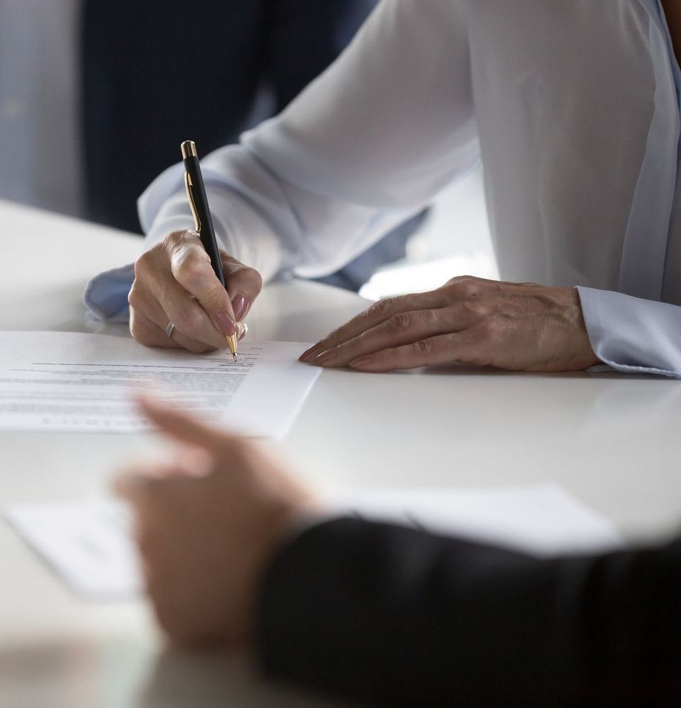 A woman is writing on a piece of paper with a pen