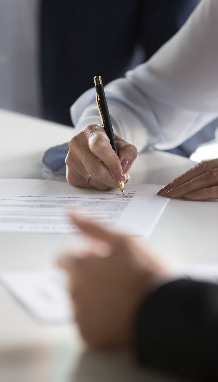 A woman is writing on a piece of paper with a pen.