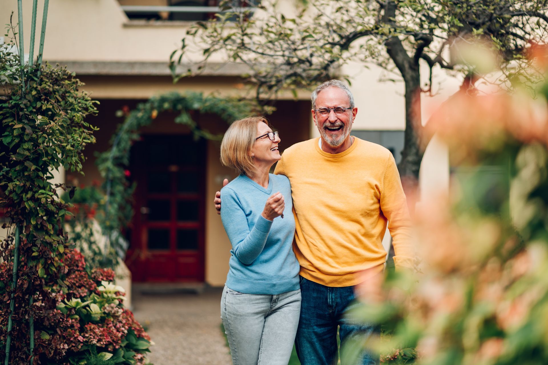 A man and a woman are standing in front of a house.