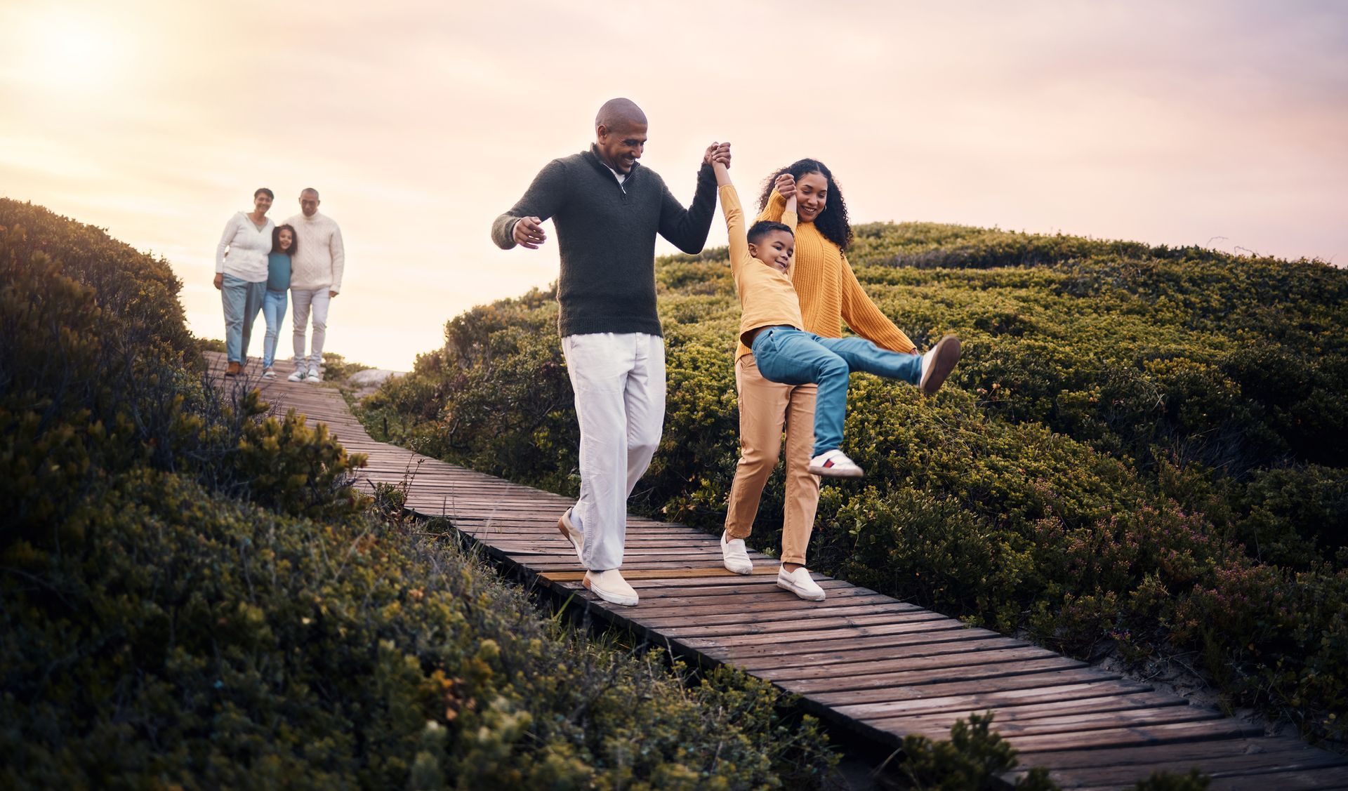 A family is walking across a wooden bridge.