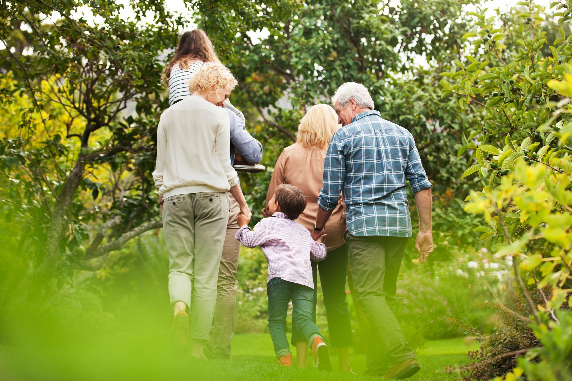 A family is walking through a park holding hands.