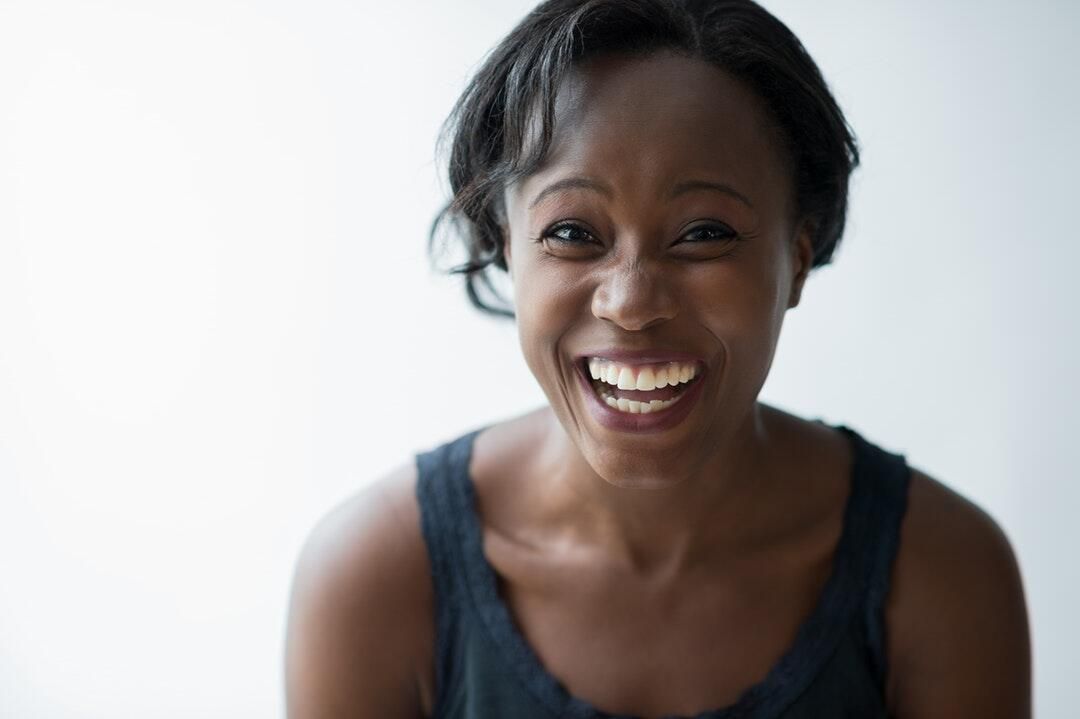 A woman in a black tank top is smiling and looking at the camera.