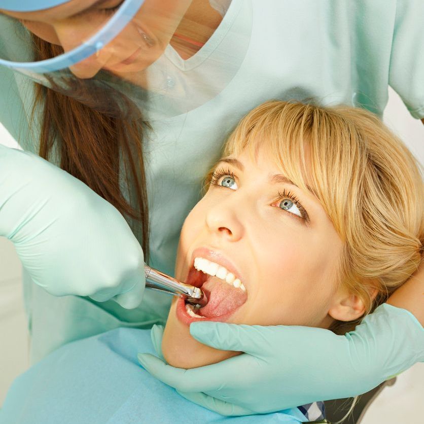 A woman is getting her teeth examined by a dentist