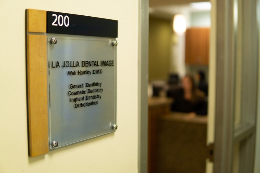 A woman is sitting at a reception desk talking to another woman.