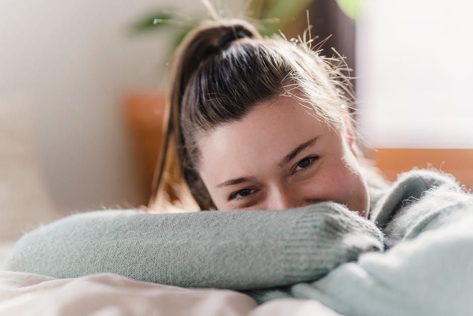 A woman is laying on a bed with her head on a pillow and smiling.