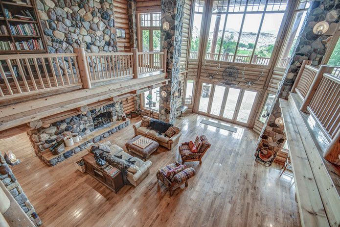 Rustic wooden house with a porch, red rock mountains in the background, green grass.