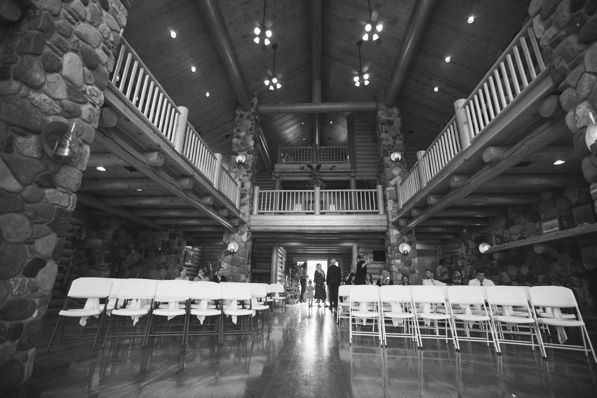 Entrance to property with white fence, gravel driveway, and metal archway under a blue sky.