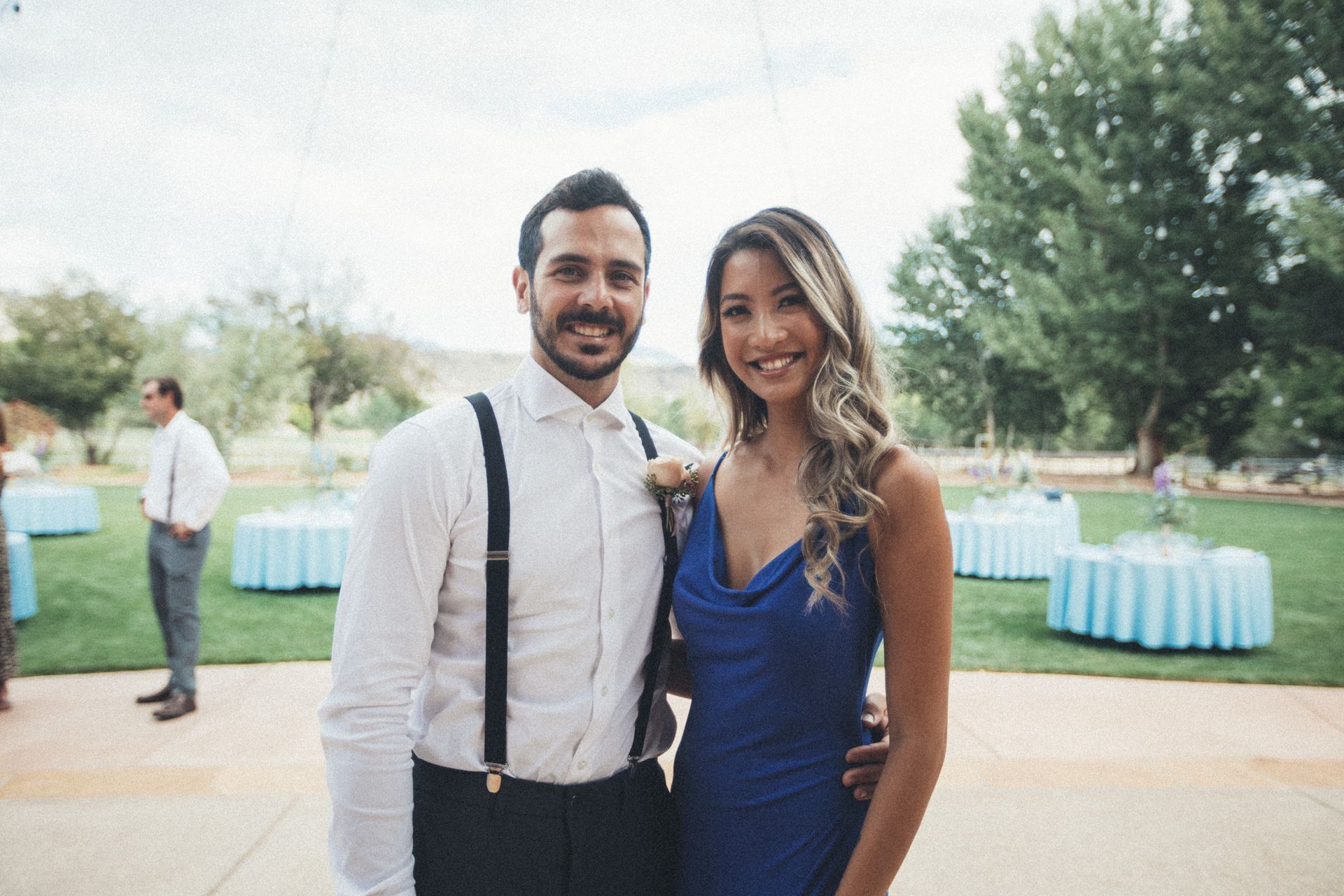 Outdoor seating arrangement: two coral armchairs and a cream sofa on grass, with a pool and trees in the background.
