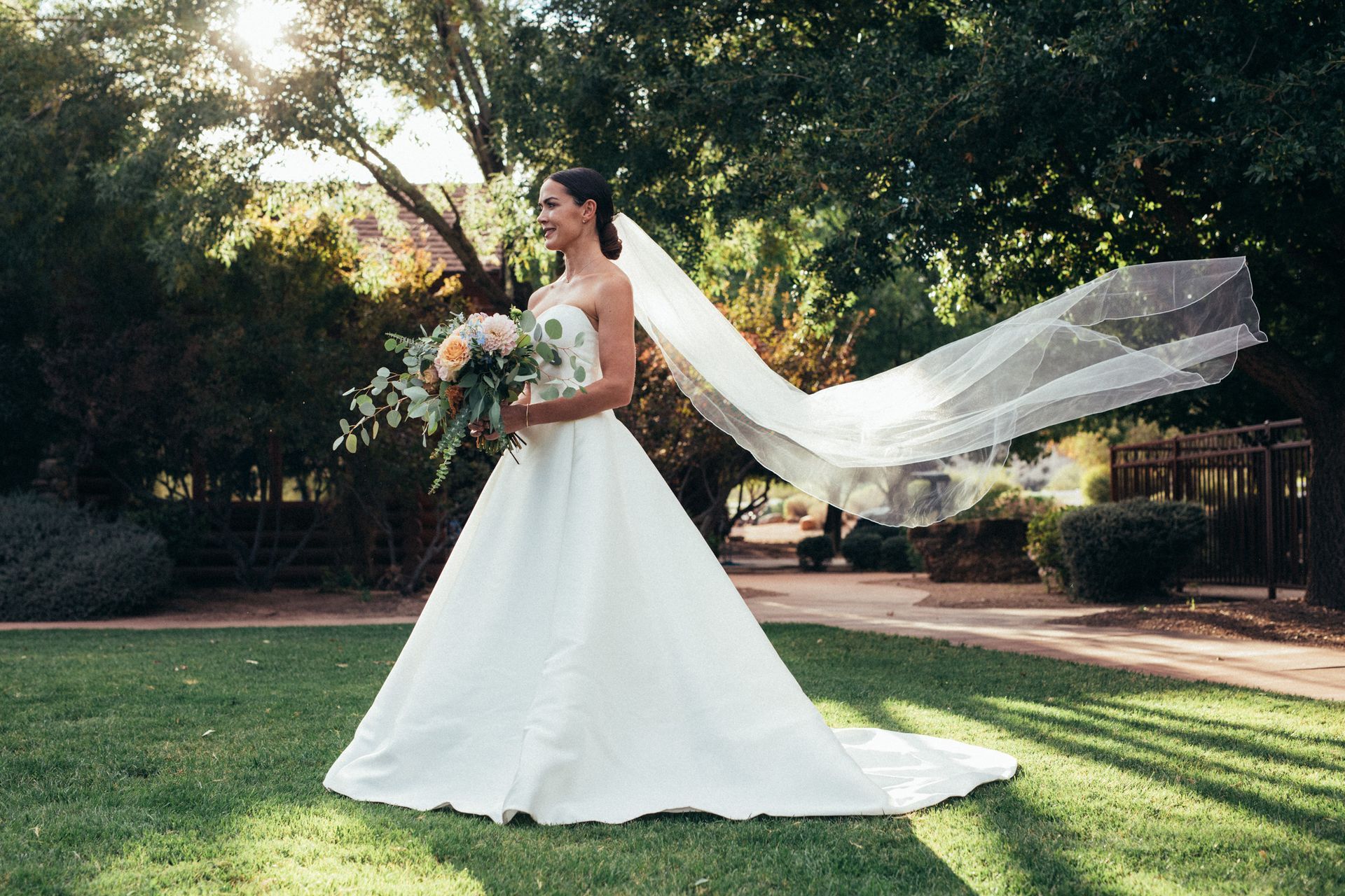 Outdoor wedding reception with guests seated at tables on a lawn near a wooden lodge.
