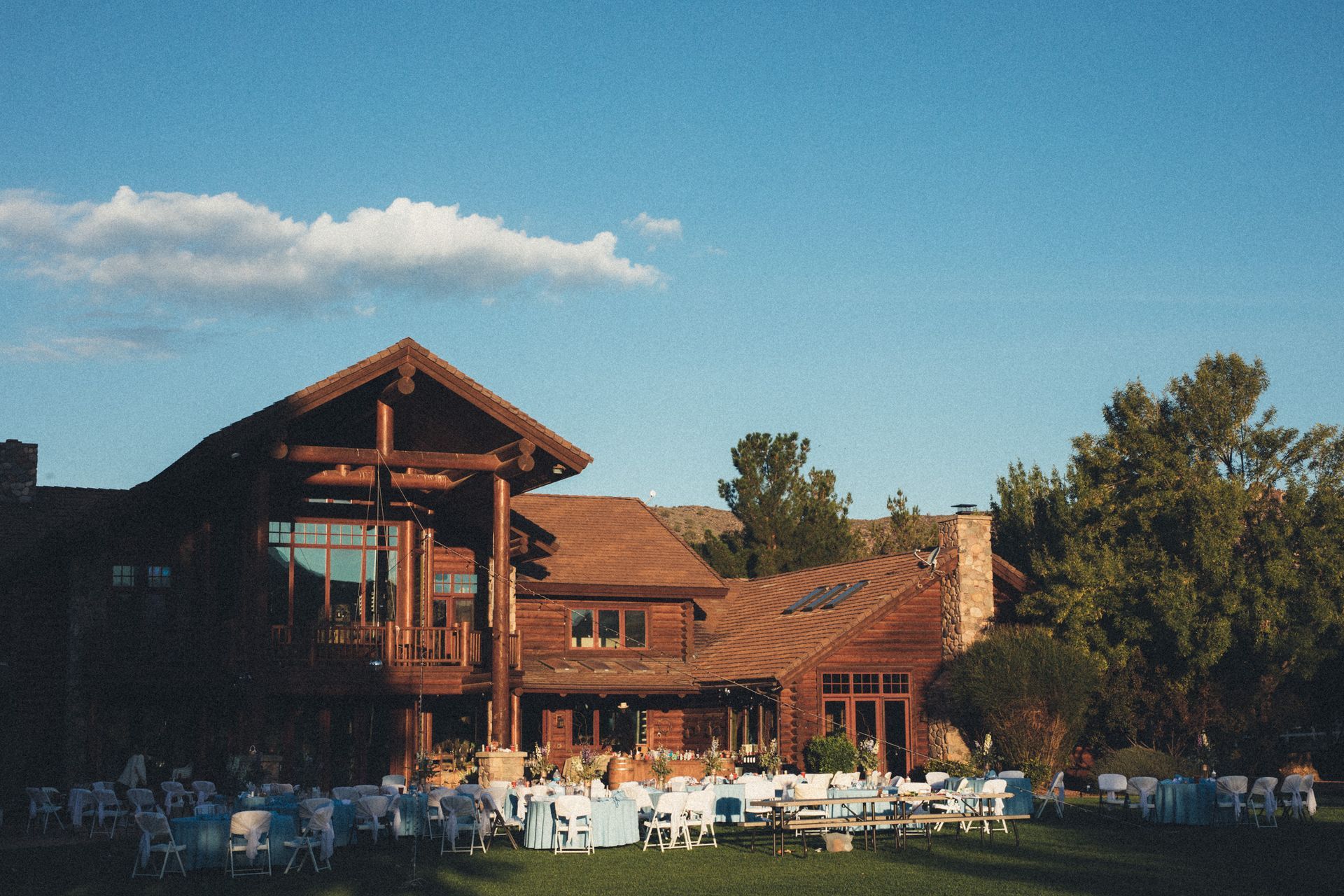 Green field framed by red rock cliffs, mountains in the distance under a blue sky.