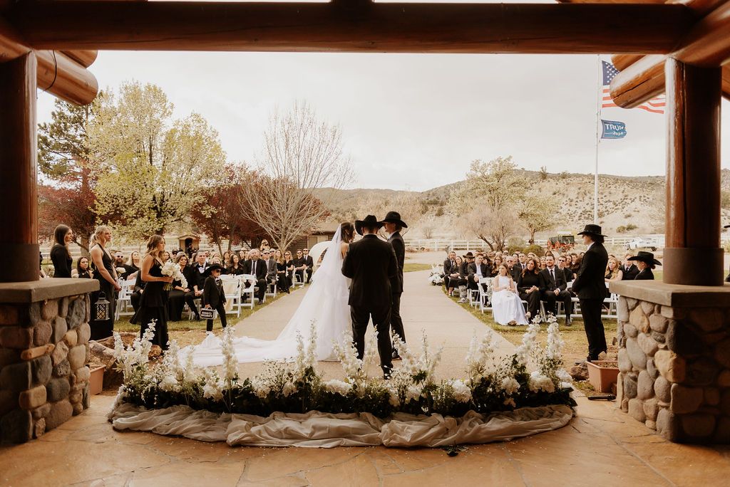 Outdoor seating arrangement: two coral armchairs and a cream sofa on grass, with a pool and trees in the background.