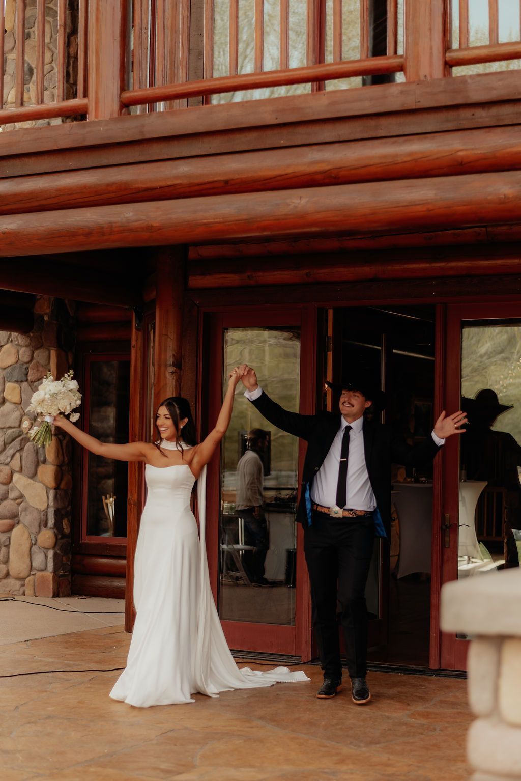Wedding ceremony setup with floral arch, benches on grass, red rock backdrop.