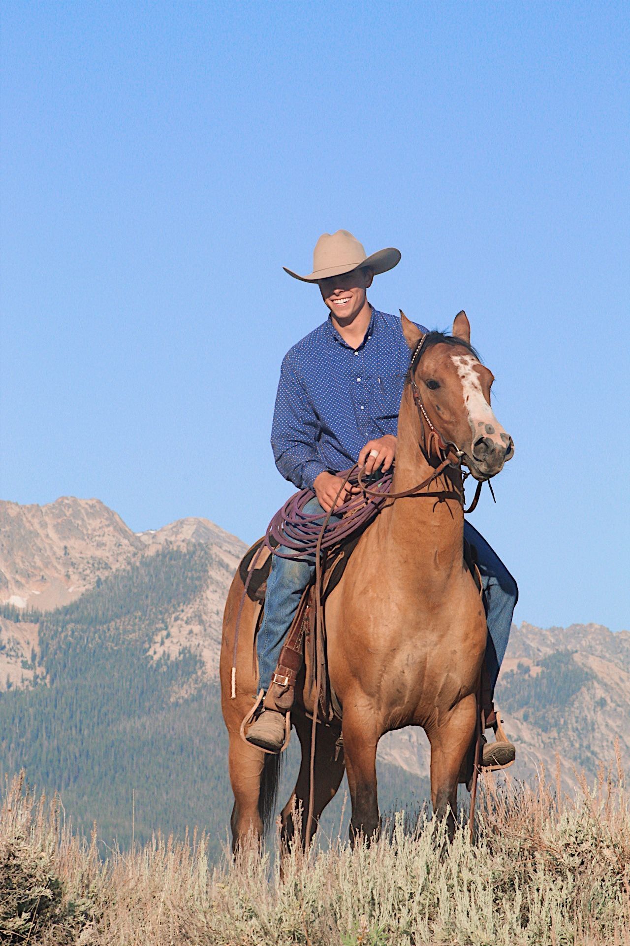 A group of people on horseback travel along a dirt trail through a desert landscape on a cloudy day.