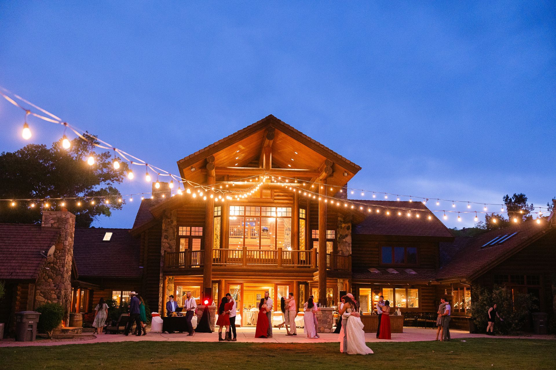 Wedding ceremony setup in front of red rock formations: wooden arch with flowers, white chairs on grass, white aisle runner.