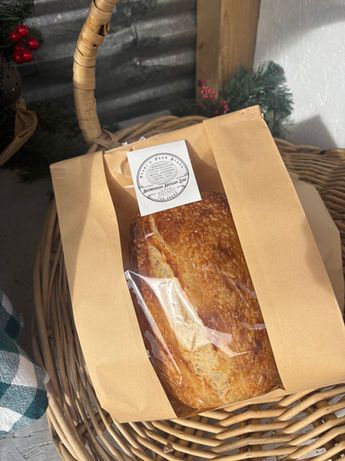 Wooden crate filled with round loaves of bread, on a wooden table, in a field setting.