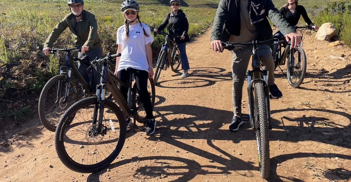A group of people are riding bicycles down a dirt road.