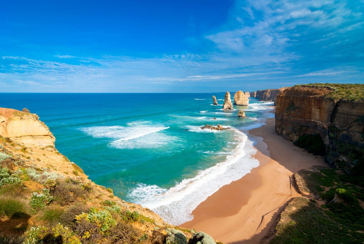 A view of a beach from a cliff overlooking the ocean.