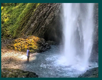 A person is standing in front of a waterfall