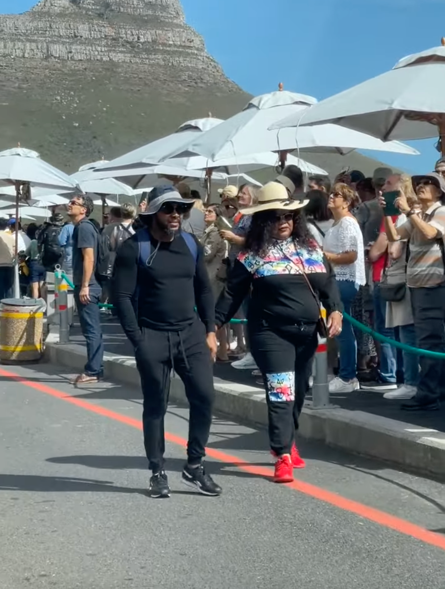 A man and a woman are walking down a street in front of a crowd of people.