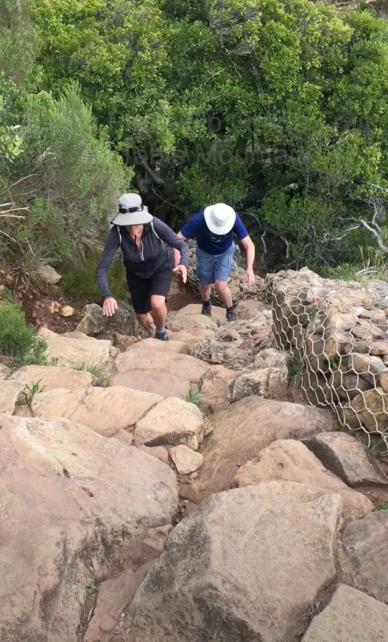 Two people are walking up a rocky hill.