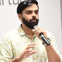 Woman in pink blazer smiles at camera.