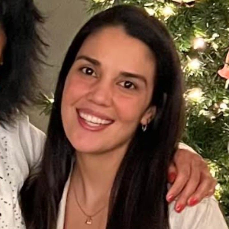 Woman in pink blazer smiles at camera.