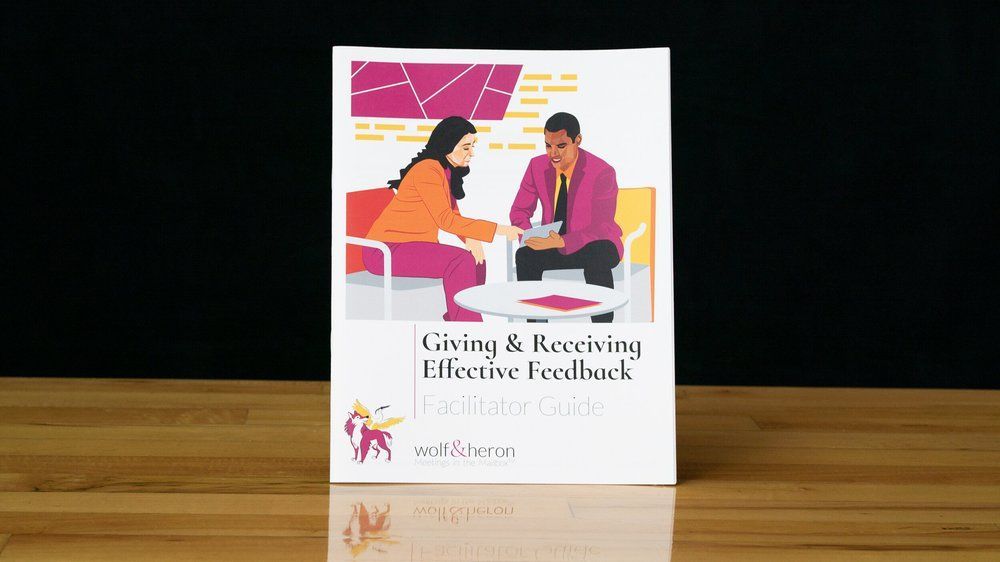 Promotional materials for giving and receiving feedback: books, stickers, pens, mug, and calendar with illustrations of two people talking.