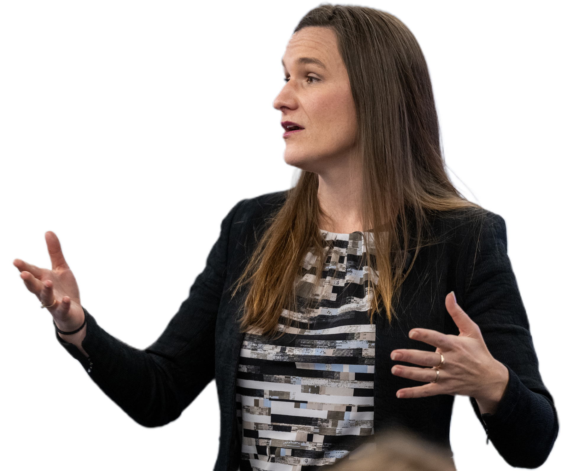Woman gesturing with hands, wearing a blazer over a patterned blouse.