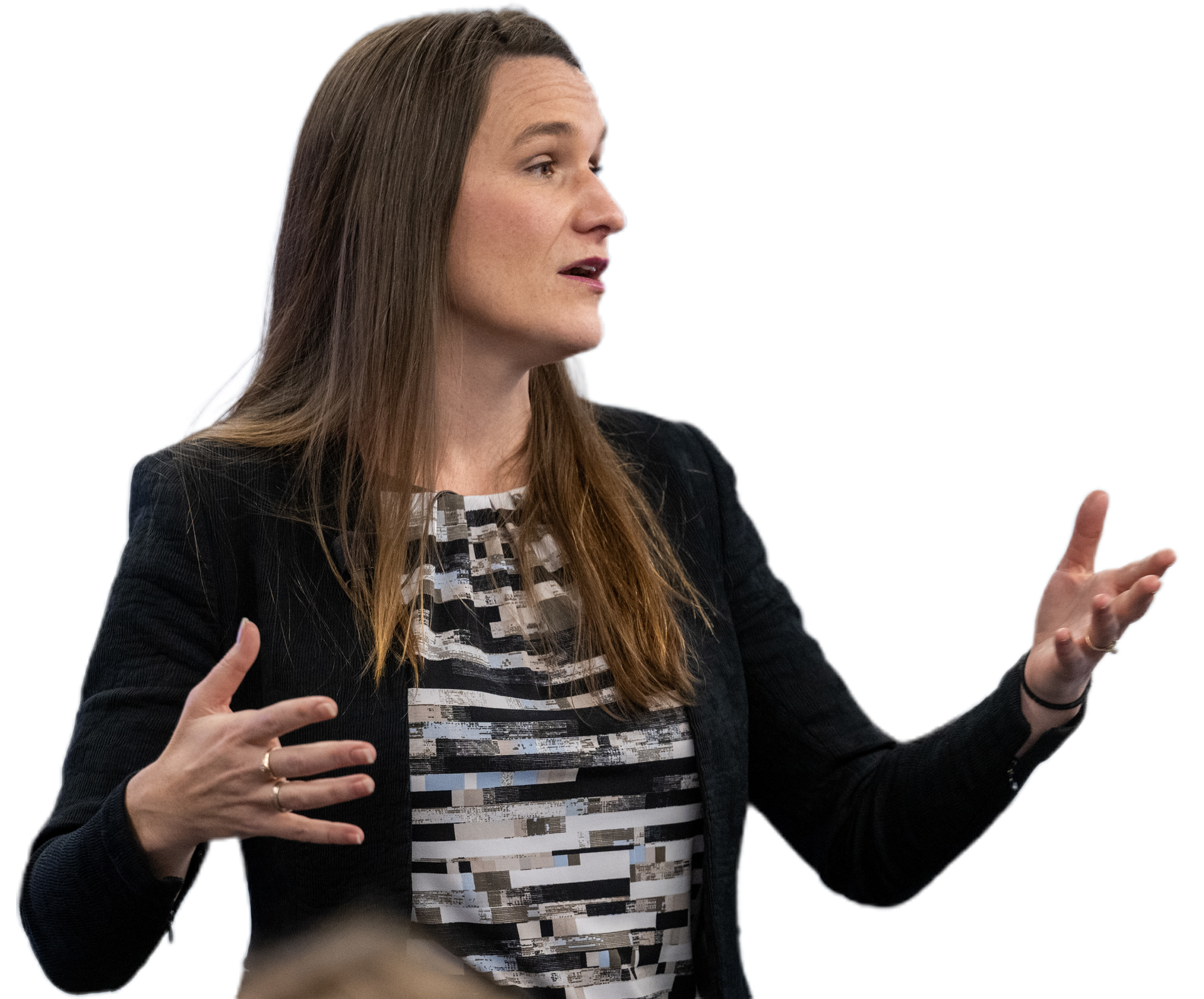 Woman gesturing with hands, wearing a blazer over a patterned blouse.