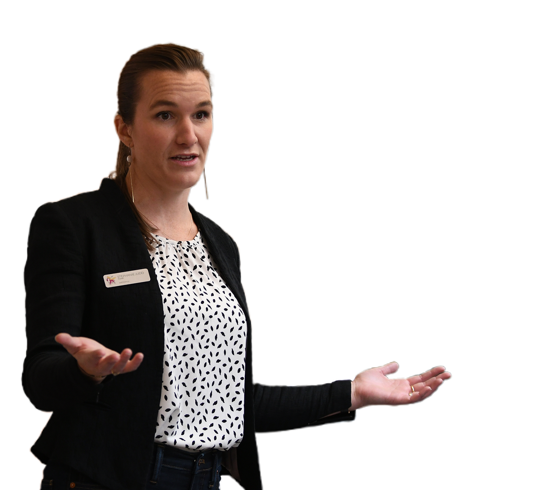 Woman wearing blazer and patterned shirt gestures with open hands, talking.